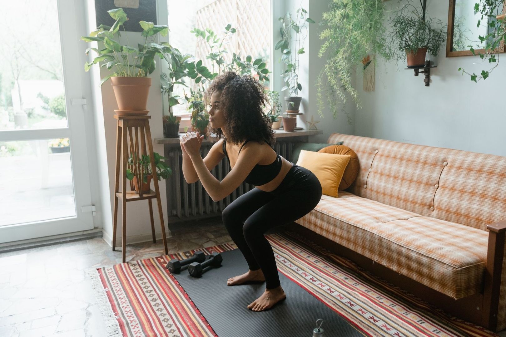 Femme réalisant un squat sur tapis avec des haltères à proximité